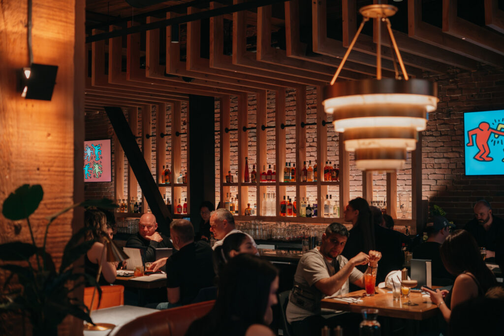 Warm Ray’s dining room with guests, bar seating, soft lighting, and lively Yaletown atmosphere.
